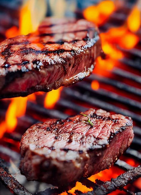 Two Steaks on a grill with fire flare-up